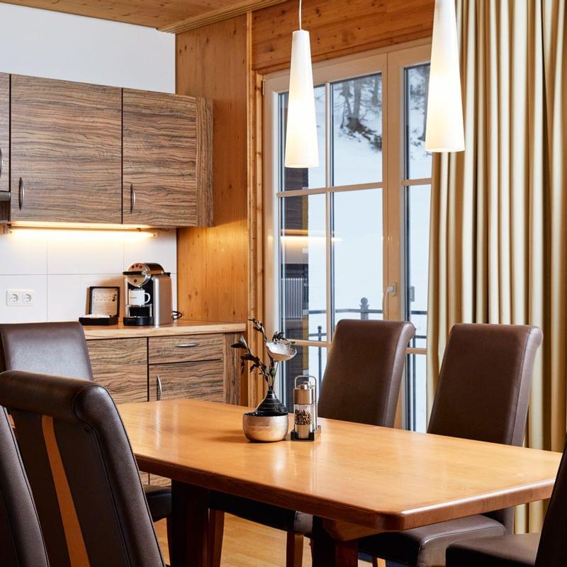 Modern wooden kitchen and dining area with brown leather chairs and pendant lights